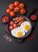 English breakfast with fried eggs, bacon, beans, tomatoes, spices and herbs photo