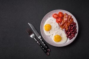 English breakfast with fried eggs, bacon, beans, tomatoes, spices and herbs photo