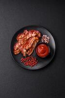 Delicious fresh fried bacon with salt and spices on a dark background photo