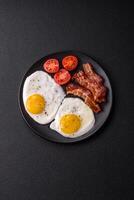 English breakfast with fried eggs, bacon, beans, tomatoes, spices and herbs photo