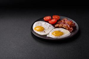 desayuno inglés con huevos fritos, tocino, frijoles, tomates, especias y hierbas foto