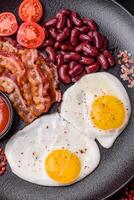 English breakfast with fried eggs, bacon, beans, tomatoes, spices and herbs photo