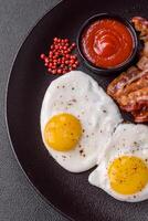 English breakfast with fried eggs, bacon, beans, tomatoes, spices and herbs photo