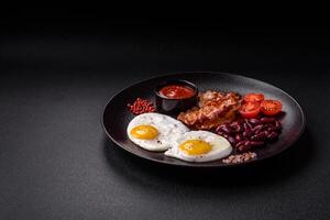 English breakfast with fried eggs, bacon, beans, tomatoes, spices and herbs photo