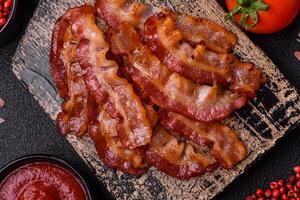 Delicious fresh fried bacon with salt and spices on a dark background photo