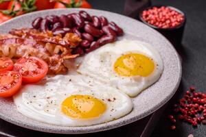 desayuno inglés con huevos fritos, tocino, frijoles, tomates, especias y hierbas foto