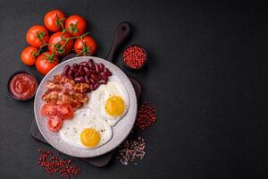 English breakfast with fried eggs, bacon, beans, tomatoes, spices and herbs photo