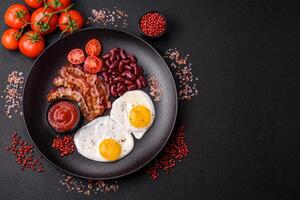 desayuno inglés con huevos fritos, tocino, frijoles, tomates, especias y hierbas foto