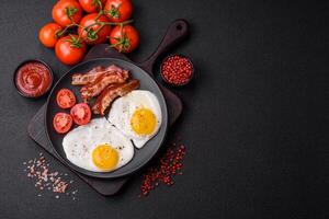 English breakfast with fried eggs, bacon, beans, tomatoes, spices and herbs photo