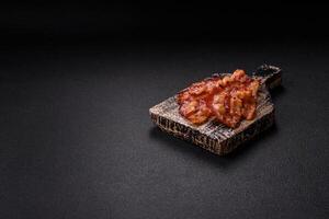 Delicious fresh fried bacon with salt and spices on a dark background photo