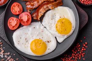 English breakfast with fried eggs, bacon, beans, tomatoes, spices and herbs photo