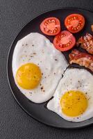 English breakfast with fried eggs, bacon, beans, tomatoes, spices and herbs photo