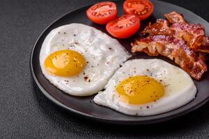 English breakfast with fried eggs, bacon, beans, tomatoes, spices and herbs photo