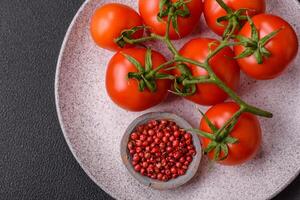 Fresh red cherry tomatoes on a branch on a dark concrete background photo