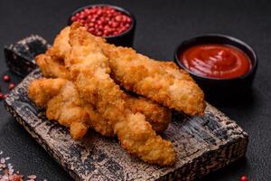 Delicious fresh chicken or turkey strips or nuggets breaded with salt and spices photo