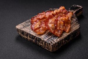 Delicious fresh fried bacon with salt and spices on a dark background photo