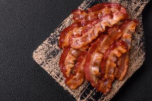 Delicious fresh fried bacon with salt and spices on a dark background photo