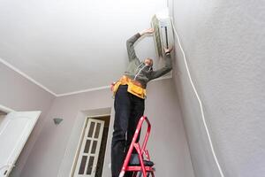 técnico masculino que limpia el aire acondicionado en el interior foto