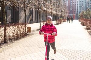 Little cute girl riding a scooter on a path in the park photo