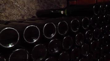 Wine bottles lying in stack at cellar. Glass bottles of wine stored in stone cellar in tavern. 4K video