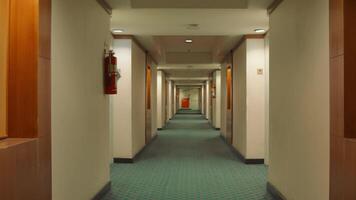 Empty hotel corridor with patterned carpet, doors on both sides, and fire extinguisher on wall. video