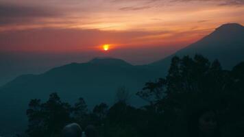 heiter Sonnenuntergang Über bergig Landschaft mit Silhouetten und beschwingt Himmel. video