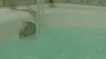 Water flowing into a bathtub with a green bath bomb dissolving, creating a relaxing spa atmosphere. video