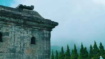 Ancient temple ruins with foggy background and lush green trees under a blue sky. video