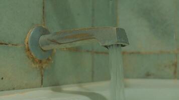 Old rusty tap with water running, showing signs of decay and neglect against a tiled background. video