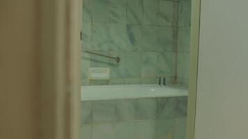 parziale Visualizza attraverso un socchiuso porta in un' moderno bagno con un' bicchiere doccia allegato. video
