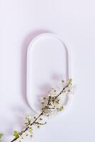 Empty white podium with spring bloom top view. Mock up for cosmetic products photo