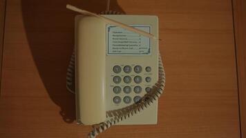 Vintage beige push-button telephone with coiled cord on wooden background. video