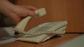 Close-up of a person's hands dialing a landline telephone, with a blurred background. video