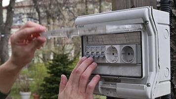 Kyiv, Ucrânia. abril 3, 2024. fechar-se do uma mão girando em uma luz interruptor e uma luz lâmpada dentro a jardim video