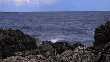 Storm at sea. Big waves break on the rocky shore, white foam on the water. Slow motion video