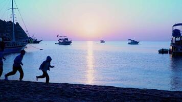 Dad with children running along the beach. Healthy lifestyle. Beautiful sunrise over the Mediterranean Sea. video