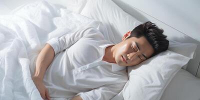 AI generated Asian man in white clothes lies on a white bed and sleeps happily. Generative AI photo