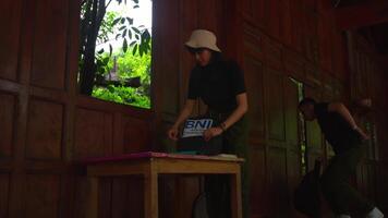 a man and woman getting ready with their belongings inside their wooden house video