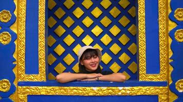 Smiling young person with a cap against a blue and yellow geometric patterned background. video