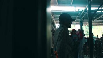 Silhouette of a person waiting at a bus station with soft focus background of passengers and structure. video