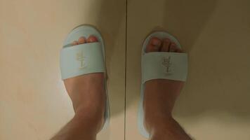 Close-up of feet in blue flip-flops on a beige background with soft lighting and shadow play. video