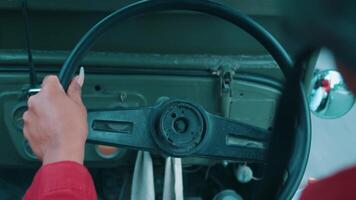 Close-up of a person's hand on the steering wheel of a vintage car, with a blurred dashboard background. video