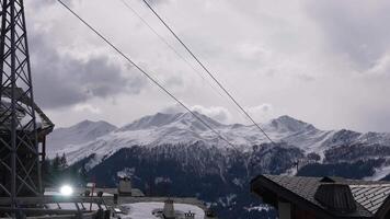 aéreo Disparo de más verboso, Suiza, muestra nieve cubierto pendientes, esquí ascensores con telesillas para esquiadores, y un estación en el bien. video
