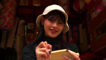 sonriente joven mujer en un sombrero escritura en un cuaderno a un acogedor cafetería. video