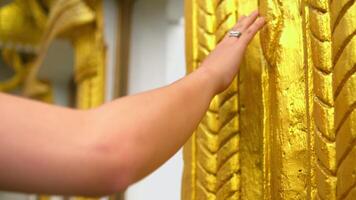 Close-up of a person's arm touching a textured golden surface, with a blurred background. video