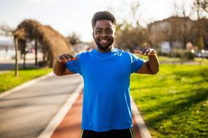 Young african-american man is exercising in the city. He is stretching his body. photo