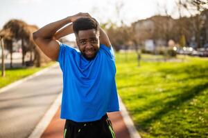 Young african-american man is exercising in the city. He is stretching his body. photo