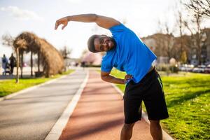 joven afroamericano hombre es hacer ejercicio en el ciudad. él es extensión su cuerpo. foto