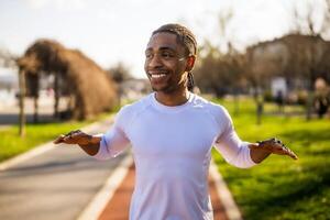 joven afroamericano hombre es hacer ejercicio en el ciudad. él es extensión su cuerpo. foto