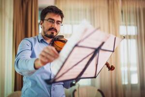 Man playing violin at home. He is practicing for live performance. photo